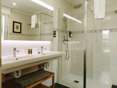 Baño privado habitación 101 Baño moderno con ducha, lavabo doble y toallas blancas colgadas. Decoración minimalista.